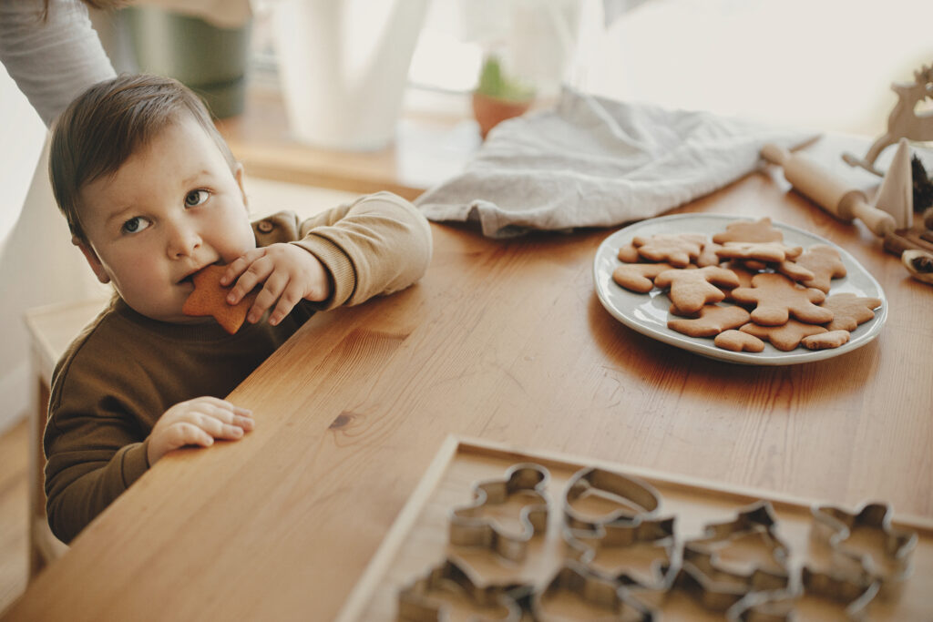 Baby eating a freshly baked gingerbread cookie.