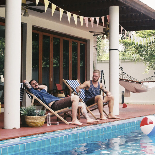 Two men sitting by a pool enjoying summer.