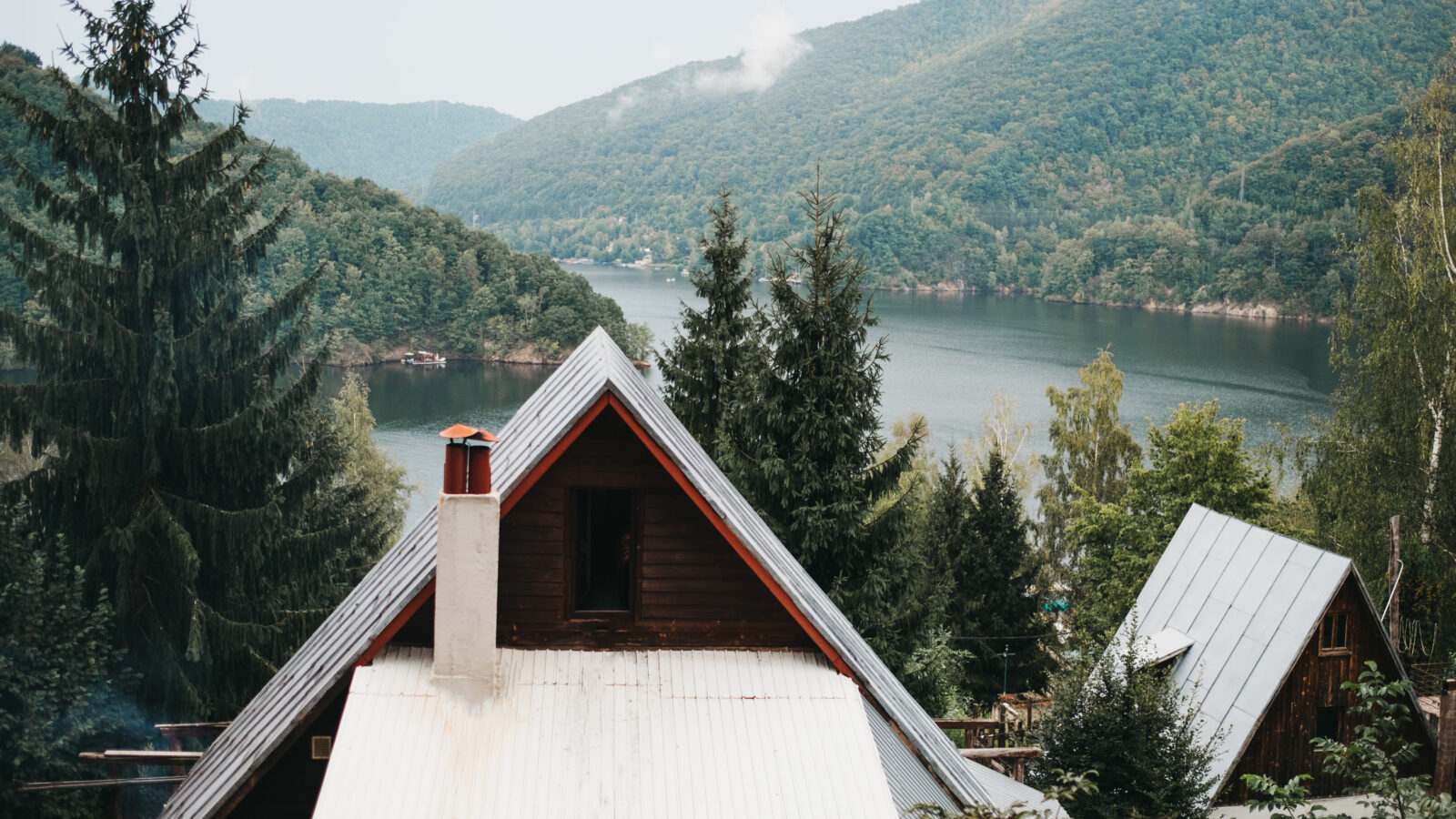 Wooden house with a tin roof overlooking a lake.