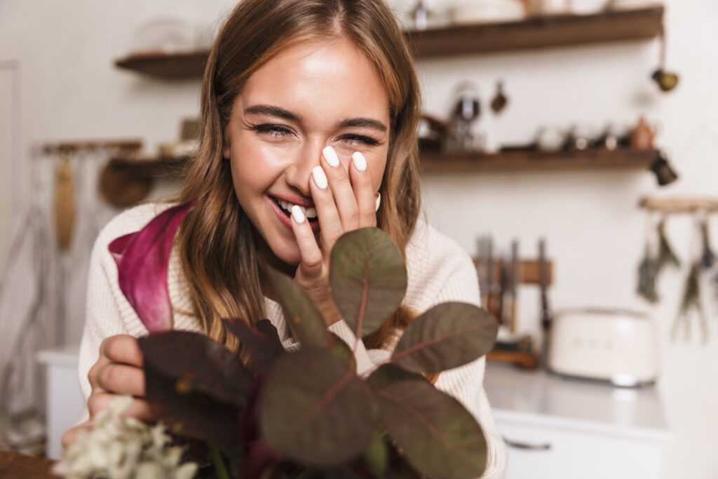 Image of a woman smiling and touching flowers.