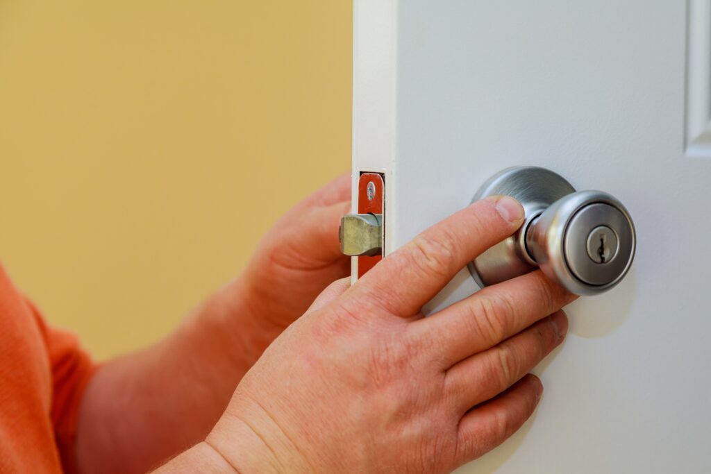 Close-up of a person's hands installing a generic door lock.