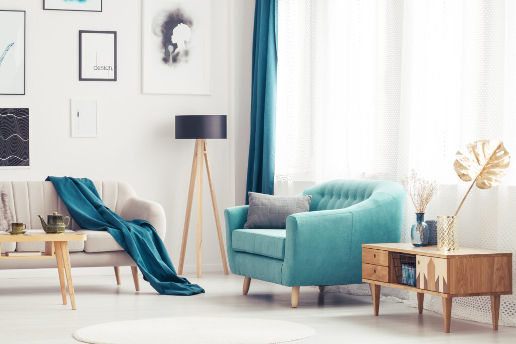 A cozy living room setting with a blue armchair and wooden cupboard.