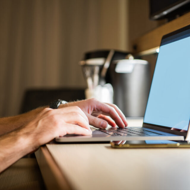 Generic picture of Men's hands on a laptop keyboard with a white screen.