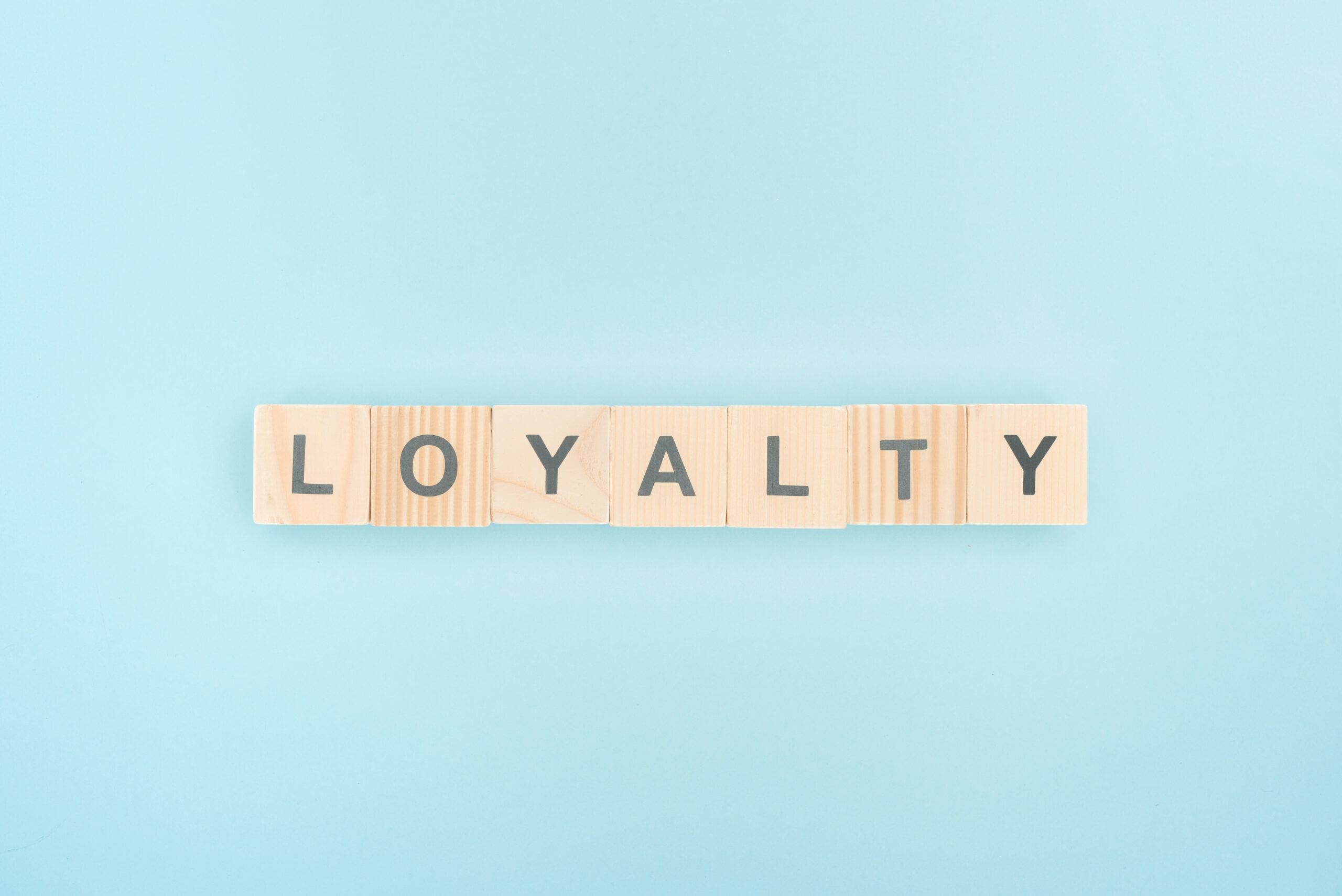 Wooden pieces with the word 'Loyalty' written in it; baby blue blank background.