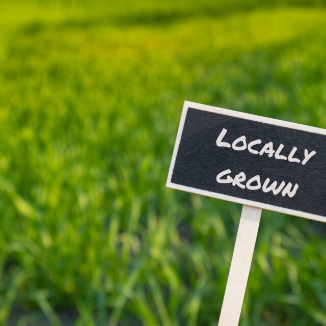 A sign that says "Locally Grown" against a grassy background.