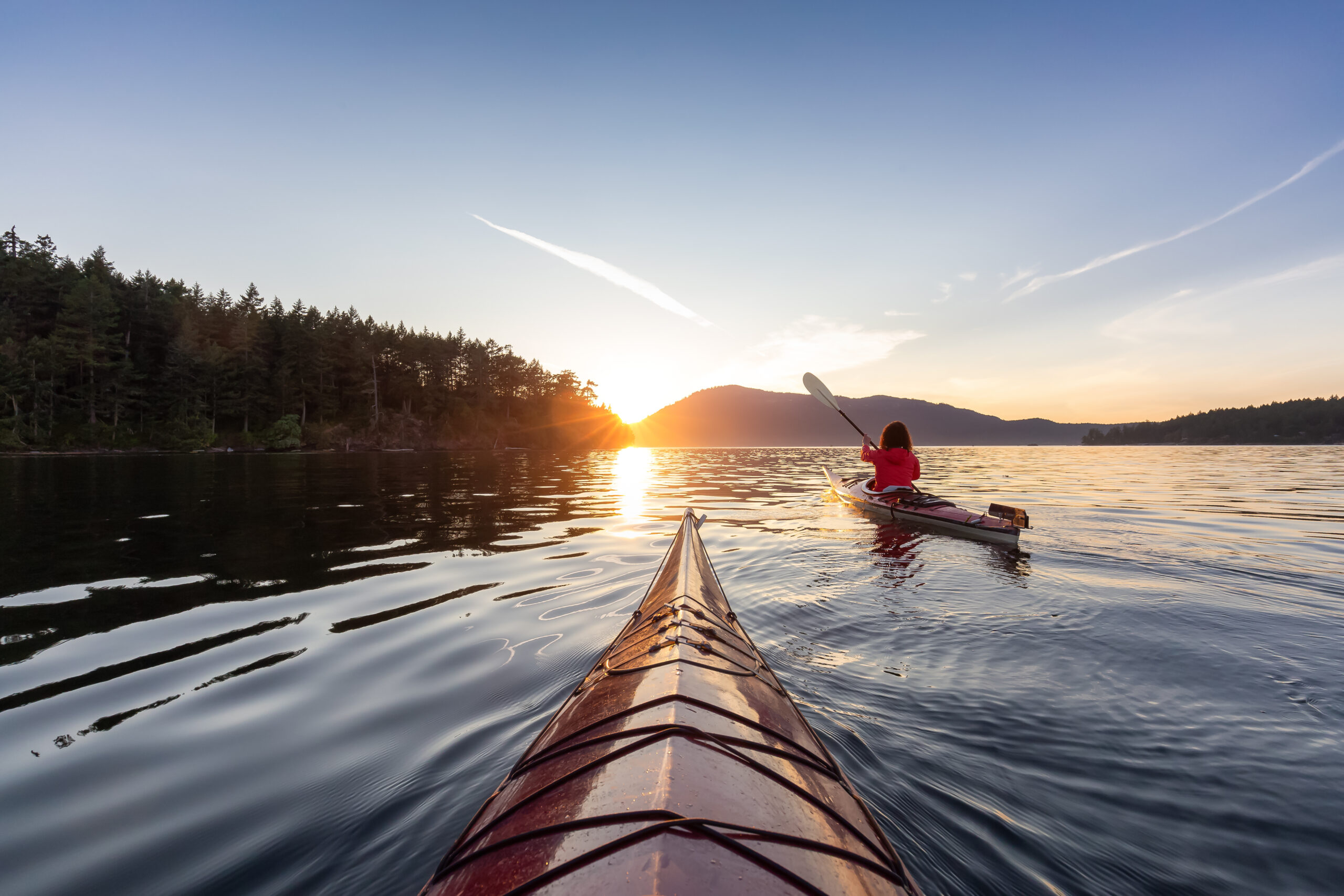 Adventurous Woman on Sea Kayak paddling in the Pacific Ocean. Sunny Summer Sunset. Taken near Victoria, Vancouver Islands, British Columbia, Canada. Concept: Sport, Adventure